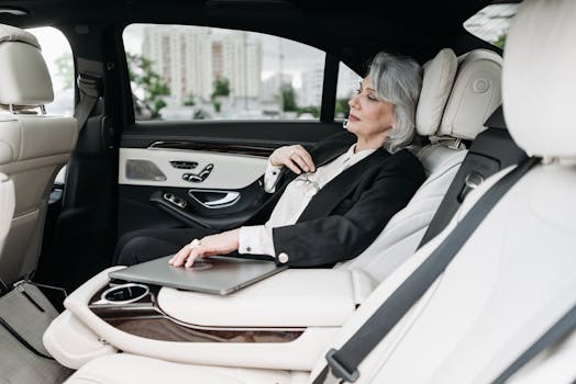 pexels-photo-8425023-8425023 Senior woman in a luxury car with a laptop, gazing out the window, representing business travel.